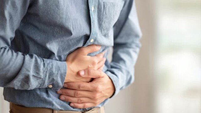 Man Suffering from Abdominal Pain: A person is clutching their abdomen in distress, likely due to discomfort. Emphasizing healthcare and bodily health