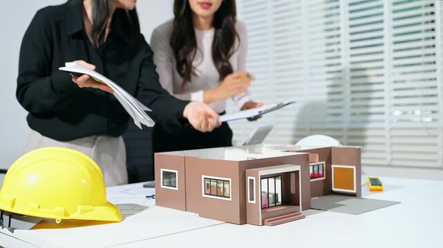 Professional architects using laptop and tablet beside modern house model, digital architecture planning, construction project management and real estate development concept.