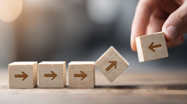 Human hand places a wooden block with a left arrow next to blocks showing a right arrow, symbolizing change in direction