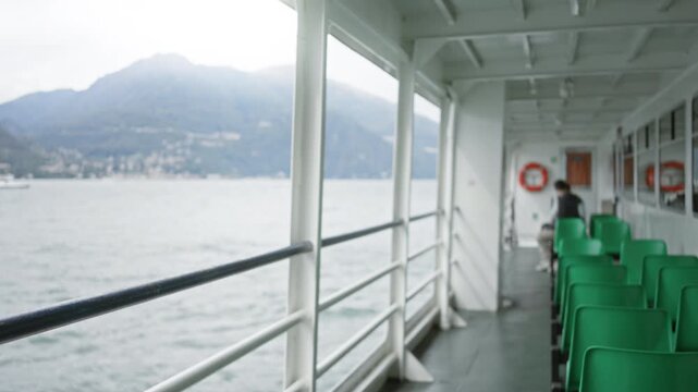 Ferry deck with soft defocused view of railing, sea and mountains, shallow focus interior; background backplate copyspace calm.