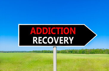Addiction recovery symbol. Concept words Addiction recovery on beautiful black road sign. Beautiful blue sky green grass field background. Psychology addiction recovery concept. Copy space.