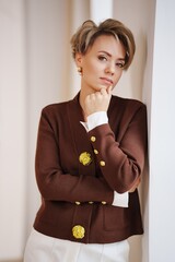 Woman poses thoughtfully in a stylish outfit indoors during the day