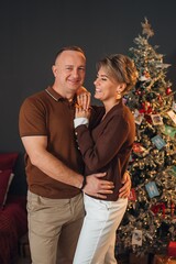 Couple smiles together in front of a decorated Christmas tree