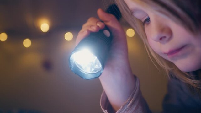 Dreamy atmosphere as young child use flashlight to read book at night
