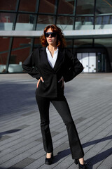 Obraz premium Confident Businesswoman Standing With Hands On Hips Near Office Building