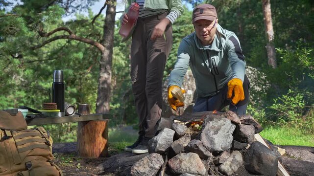 Young couple preparing meal in Finnish national park protected area. Sustainable eco-tourism and nature conservation concept with authentic lifestyle and mental wellness in sunny forest.