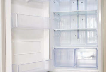 Modern open refrigerator close-up with empty shelves, front view.
