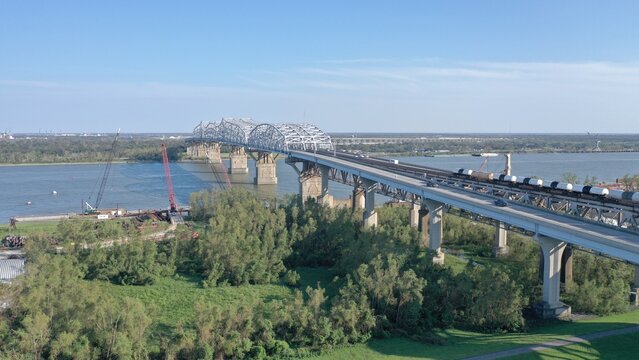 Aerial view of a long bridge over a wide river, supported by concrete pillars, under a clear sky, Baton Rouge, USA.