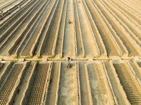 Aerial view of parallel rows of brick stacks and sandy pathways create a textured landscape under the sun, Aminbazar, Dhaka Division, Bangladesh.
