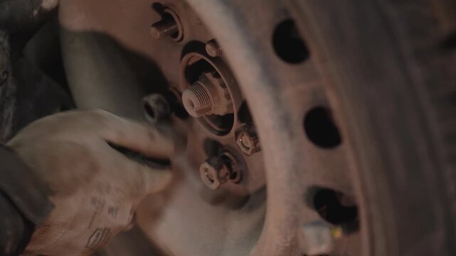 The hand of a master tightening bolts in the rim of a car wheel