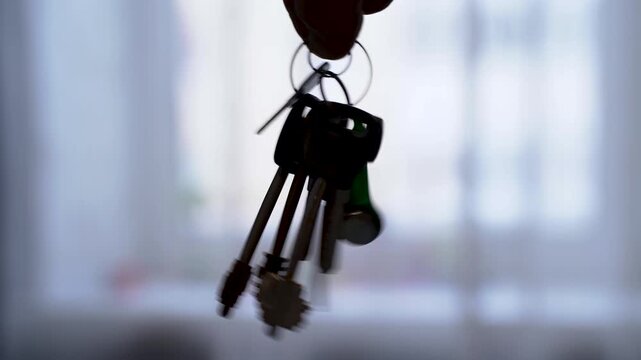 A bunch of keys in a person's hand against a window