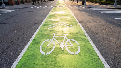 Obraz premium Green painted bike lane with arrow symbol on urban street 