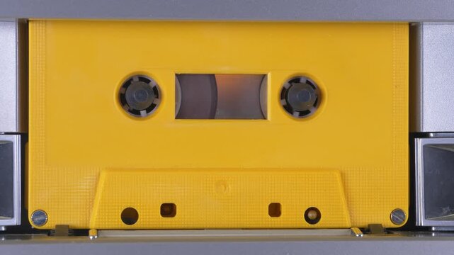 Yellow audio cassette tape moving upwards
