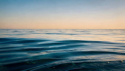 Fototapeta premium Tranquil blue water surface with subtle ripples and a gradient sky, reflecting soft evening light, creating a serene and timeless natural backdrop