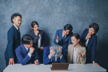 ノートパソコンの前に集合する様々な世代のスーツを着た男女