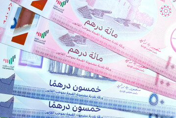 Fototapeta premium Close-up of United Arab Emirates Currency: AED Banknotes and Dirham Coins Scattered on Surface