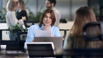 Fototapeta premium A man is sitting at a desk with a laptop and a piece of paper
