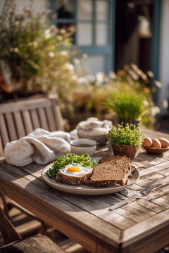 Minimalist outdoor breakfast setup on a wooden table with rye bread, soft-boiled eggs, and fresh greens. The setting glows in crisp Scandinavian morning light, with a simple garden just beyond.
