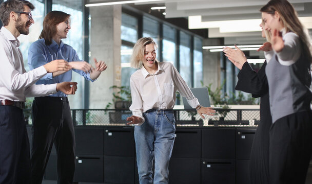 A group of people are standing in a room, one of them is wearing jeans