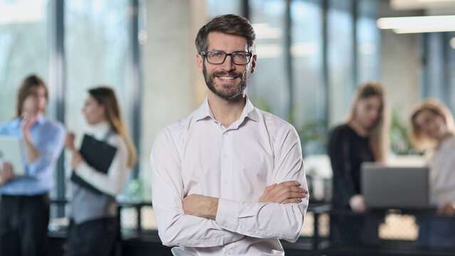 A man in a white shirt is smiling and standing in front of a group of people