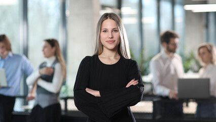 A woman in a black sweater stands in front of a group of people © ASDF