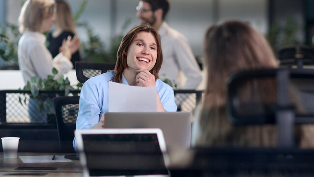 A man is sitting at a desk with a laptop and a piece of paper