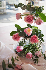 Flower decoration for a wedding table. Pink roses, tulips and ranunculus arranged on a tiered stand. Vertical lifestyle background for festive occasions.