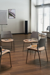Empty modern meeting room showing arrangement of chairs in circle with notebooks and pens placed on...