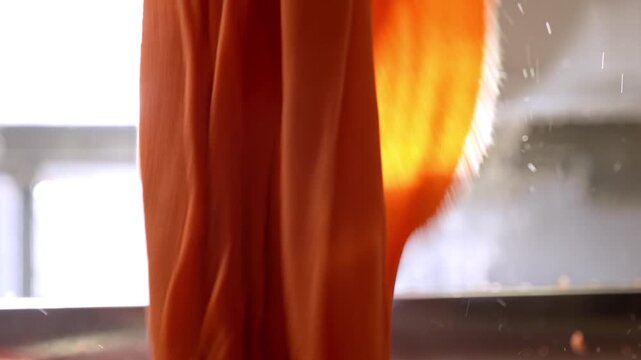 Bright orange fabric flowing from large dyeing machines in a textile factory. Professional industrial footage reflecting technical process, production control and large scale manufacturing.