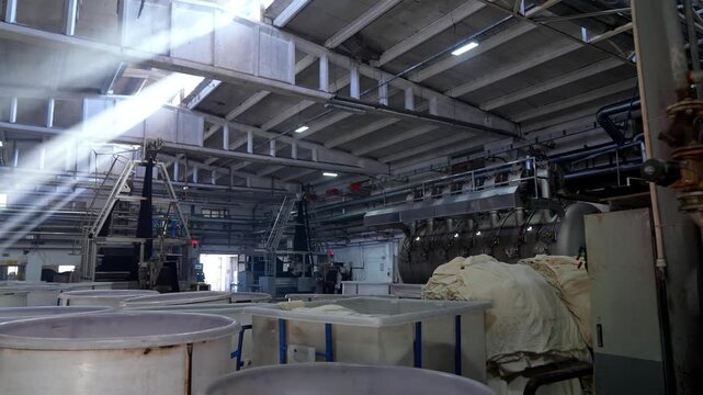 Wide view of a modern textile factory with large dyeing machines and processing equipment. Professional industrial footage reflecting large scale manufacturing environment and workflow.