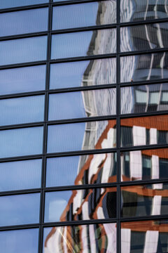 Modern corporate building with glass facade windows and reflections creating urban architecture pattern on contemporary exterior in office district with clean design lines