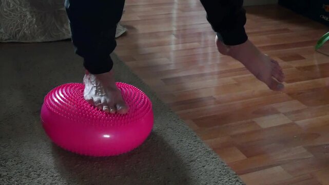 Man performing balance exercise on a pink stability disk, demonstrating fitness and proprioception training for rehabilitation