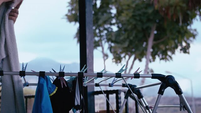 Female Hanging Washed Laundry Outdoors on Veranda with Picturesque Mountain View