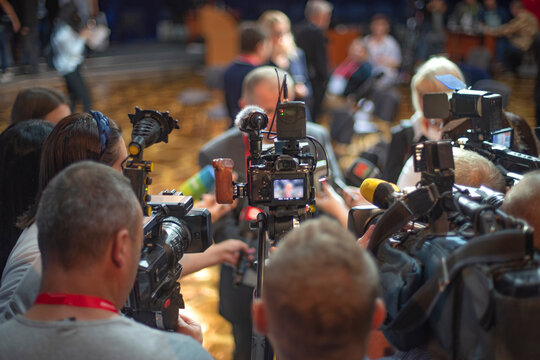 Crowded Press Conference with Video Cameras and Microphones for Breaking News Concept