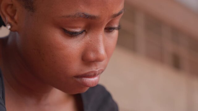 black teen student closeup looking down, tearful expression with beads of sweat, indoor classroom background, pensive mood and study fatigue, exam aftermath, cinematic warm lighting, authentic emotion