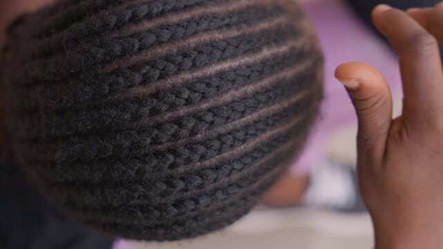 Child examines scalp. Young child delicately feels textured scalp with gentle fingers. An adorable child gently tracing intricate lines of cornrows on their scalp with care and curiosity