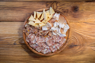 Round wooden board mountain affettati: felino salami, raw prosciutto, speck, colonnata lardo, pecorino grana cheeses, rustic appetizing traditional Italian mood