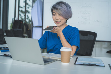 Senior Doctor Using Voice Message on Smartphone at Desk