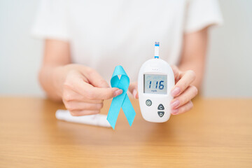 Hand show Blue Ribbon and digital blood glucose meter with lancet pen. high blood sugar level,...