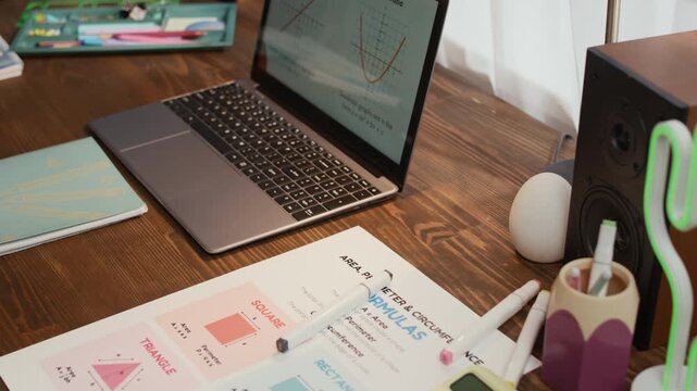 Close up of paper with math formulas, working laptop and different notebooks on top of wooden table