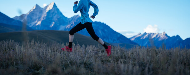 Fitness woman trail runner running in grassland
