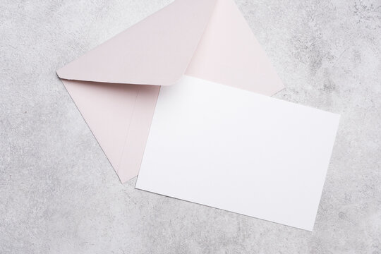 Blank invitation or greeting card mockup with a soft pink envelope placed on a textured gray background, ideal for customizable designs and personal messages