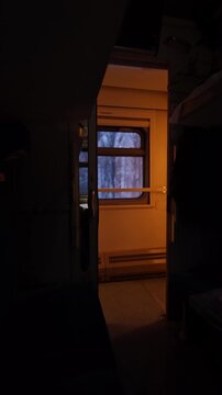 Interior view from a train compartment showing a window with a glimpse of a snowy landscape, illuminated by warm light, capturing the cozy atmosphere of night-time travel in winter