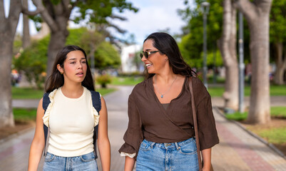 Obraz premium Two young women friends walking outdoors, having a happy conversation in a park