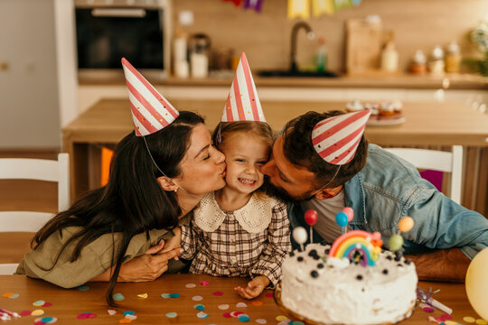 Adoring adults celebrating child's birthday with cake
