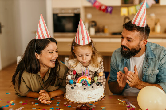 Young girl blowing out candles on cake