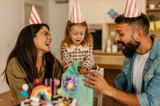 Family watching child opening presents at home