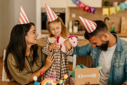 Family celebrating child's special day receiving unicorn gift