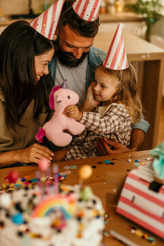 Family unwrapping unicorn toy receiving home surprise