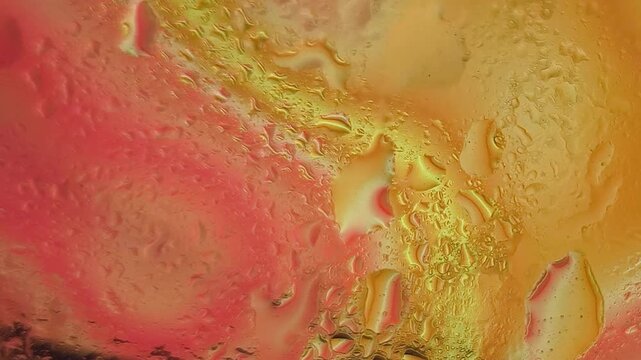 Abstract close-up shot of melted wax or oil with vibrant orange, yellow, and red hues and a textured surface against a plain white background.
